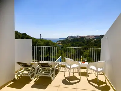a balcony with a table and chairs and the ocean at Casa Turquesa in Salema