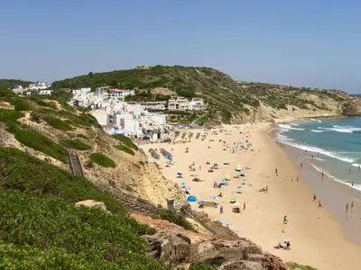 a group of people on a beach next to the ocean at Casa Turquesa in Salema