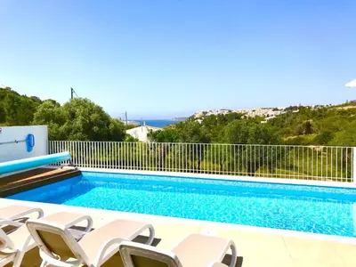 a pool with chairs and the ocean in the background at Casa Turquesa in Salema