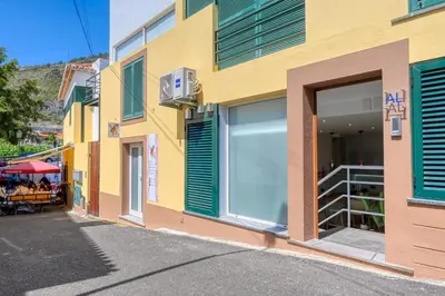 a yellow building with green shutters on a street at Seashell, a Home in Madeira in Machico