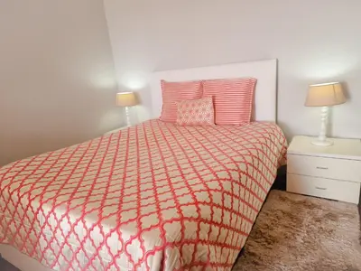 a bedroom with a bed with a orange and white comforter at Basilio's Villa in Funchal