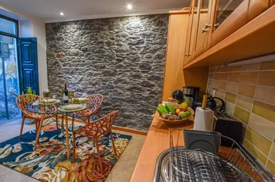 a kitchen with a table and chairs and a stone wall at Casa Laurinda Funchal in Funchal