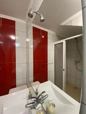 a bathroom with a sink and a shower and a mirror at Guest House Santinhos in Estreito da Calheta