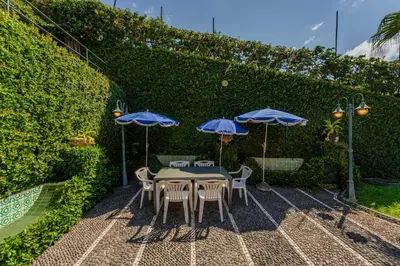 a patio with tables and umbrellas and a hedge at FLH Funchal Casa do Carvalhal in Funchal