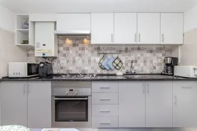 a white kitchen with white cabinets and appliances at Apartamentos Jorge Águas - 1Bedroom Private terrace & Sea view in Burgau