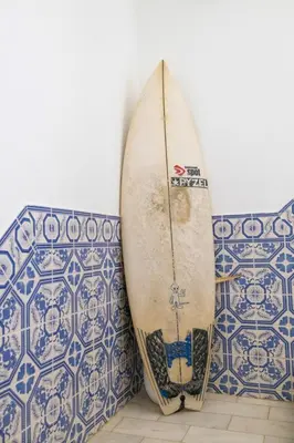 a surfboard leaning up against a wall with tiles at Apartamentos Jorge Águas - 1Bedroom Private terrace & Sea view in Burgau