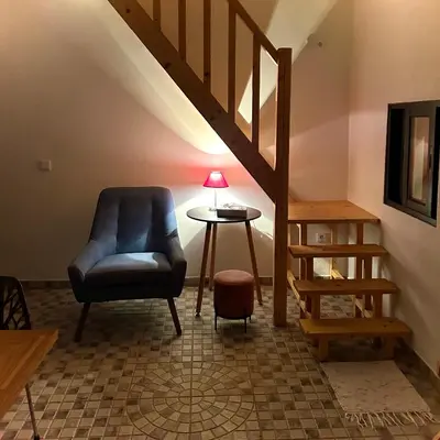 a living room with a chair and a table at As Casinhas da Madeira - Cosy Stone Cottage in a subtropical garden in Arco da Calheta
