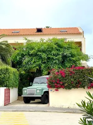 a green car parked in front of a house at Casa da Palmeira Porto Santo in Vila Baleira