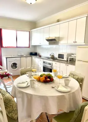 a white table with a bowl of fruit and wine glasses at Casa da Palmeira Porto Santo in Vila Baleira