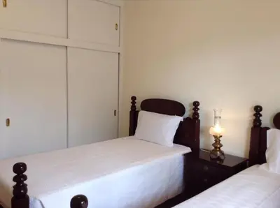 a bedroom with two beds with white sheets and a lamp at Casa da Palmeira Porto Santo in Vila Baleira