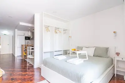 a white bedroom with a bed with a table on it at Pôr do Sol Apartment in Funchal