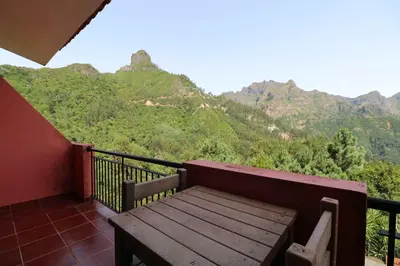 a wooden bench on a balcony with mountains in the background at Valley View Hotel Encumeada in Senhora do Rosário