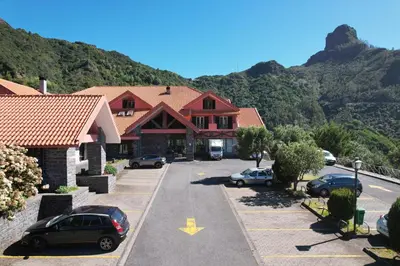 a building with cars parked in a parking lot at Valley View Hotel Encumeada in Senhora do Rosário