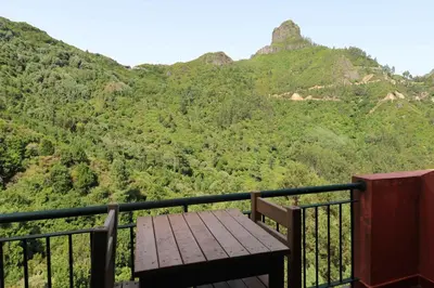 a wooden bench on a balcony with mountains in the background at Valley View Hotel Encumeada in Senhora do Rosário