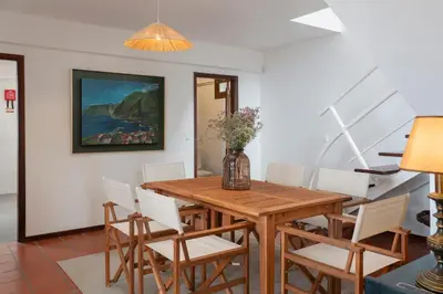 a dining room with a wooden table and white chairs at Casa Amarela da Fajã da Areia by An Island Apart in São Vicente