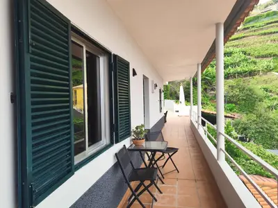a balcony with chairs and a table and windows at Quinta do Araújo - GuestHouses in Câmara de Lobos
