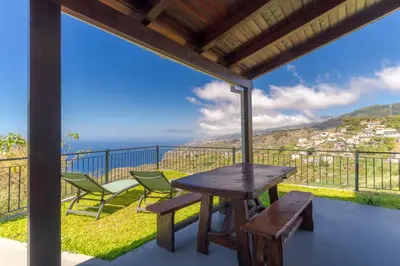 a table and chairs on a balcony with a view of the ocean at Villa Quinta Grande by Holiday rental Madeira in Quinta Grande