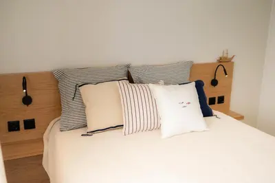 a bedroom with a white bed with striped pillows at Porto Santo Precious Oceanview in Campo de Baixo