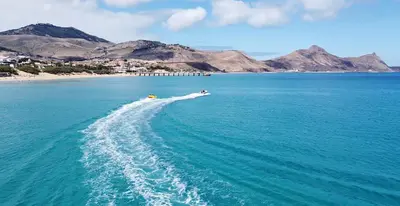 a boat in the ocean with mountains in the background at Porto Santo Precious Oceanview in Campo de Baixo