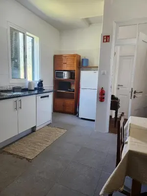a kitchen with white cabinets and a white refrigerator at Oscar House Free Parking in São Vicente