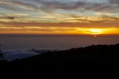 a sunset over a mountain with clouds in the sky at Golden Moon, Ponta do Sol in Ponta do Sol