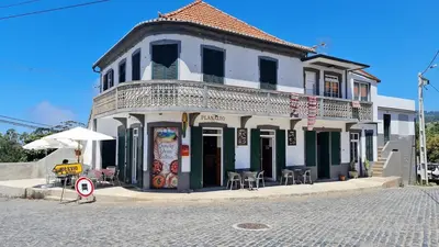 a white building with tables and chairs on a street at Golden Moon, Ponta do Sol in Ponta do Sol