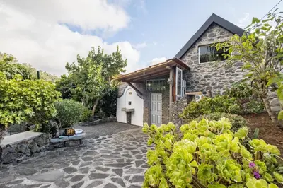 an exterior view of a stone house with a garden at Casas Maravilha by Homie in Calheta