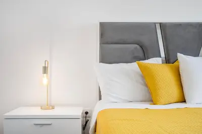 a bed with yellow and white pillows and a lamp at Brand new apartment - Balcony with sea view in Arco da Calheta