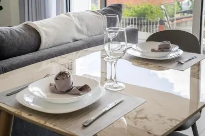 a table with two white plates and glasses on it at Brand new apartment - Balcony with sea view in Arco da Calheta