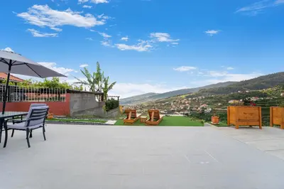 a patio with chairs and a table and an umbrella at Brand new private modern apartment with Patio and Sea View in Calheta