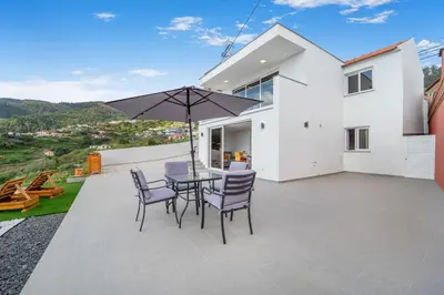a patio with a table and chairs and an umbrella at Brand new private modern apartment with Patio and Sea View in Calheta
