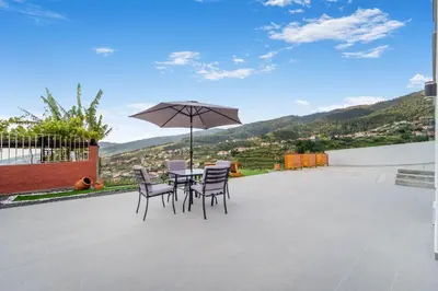 a patio with a table and chairs and an umbrella at Brand new private modern apartment with Patio and Sea View in Calheta