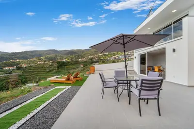 a patio with a table and chairs and an umbrella at Brand new private modern apartment with Patio and Sea View in Calheta