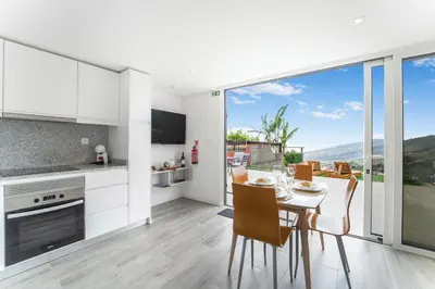 a kitchen and dining room with a table and chairs at Brand new private modern apartment with Patio and Sea View in Calheta