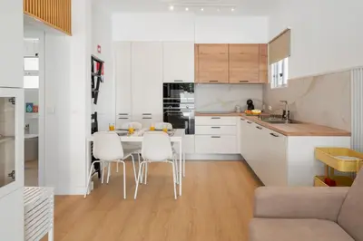 a kitchen with white cabinets and a table and chairs at Casa da Palmeira by An Island Apart in Porto Santo