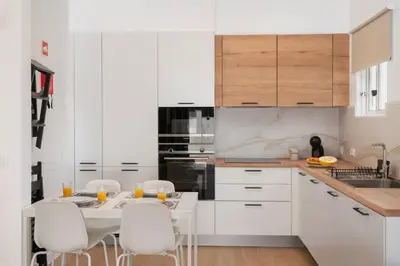 a kitchen with white cabinets and a white table and chairs at Casa da Palmeira by An Island Apart in Porto Santo