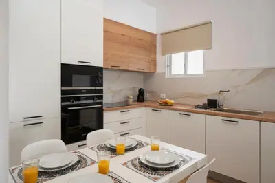a kitchen with white cabinets and a table with glasses of orange juice at Casa da Palmeira by An Island Apart in Porto Santo
