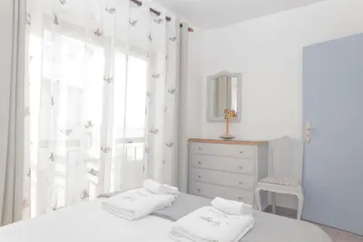 a white bedroom with a bed and a window at Apartamentos Jorge Águas - 2Bedroom in the town of Burgau - Sea view in Burgau