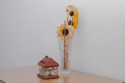 a vase with flowers and a small house on a table at Apartamentos Jorge Águas - 2Bedroom in the town of Burgau - Sea view in Burgau