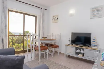 a living room with a television and a table with chairs at Apartamentos Jorge Águas - 2Bedroom in the town of Burgau - Sea view in Burgau