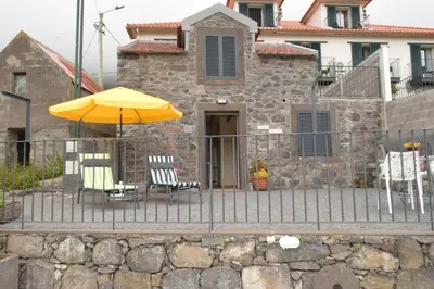 a patio with two chairs and an umbrella at Sonho Paixão in São Vicente