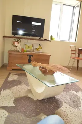 a living room with a glass table and a tv at Sonho Paixão in São Vicente
