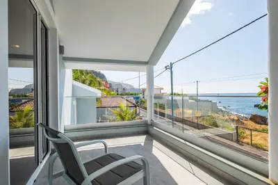 a balcony with a chair and a view of the ocean at Coastal Charm by Homie in Ponta do Sol