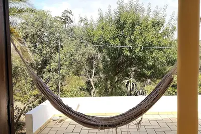 a hammock on a patio with a pool at Casa do Guarda - Arrifana beach 5min walk in Praia da Arrifana