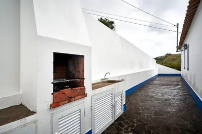 a white kitchen with a sink and a fireplace at Casa Azul da Corisca in São Lourenço