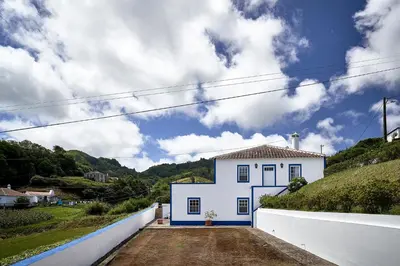 a white house on a hill with a white wall at Casa Azul da Corisca in São Lourenço
