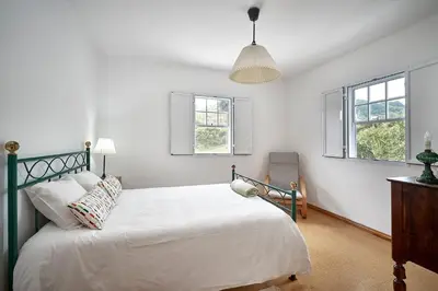 a bedroom with a bed and two windows at Casa Azul da Corisca in São Lourenço