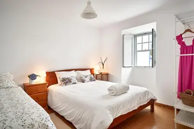 a white bedroom with a bed and a window at Casa Azul da Corisca in São Lourenço