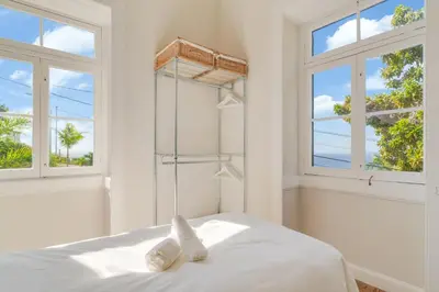 a white bedroom with windows and a bed with white sheets at Casa Trollis by Holiday Rental Madeira in Funchal