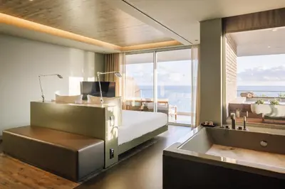 a bedroom with a bed and a tub and a sink at Saccharum - Resort and Spa - Savoy Signature in Calheta